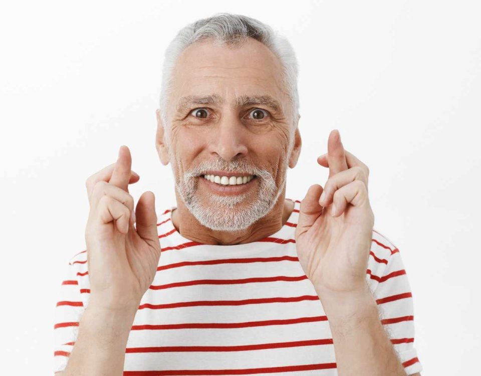 close up optimistic hopeful senior man cross finger good luck making wish